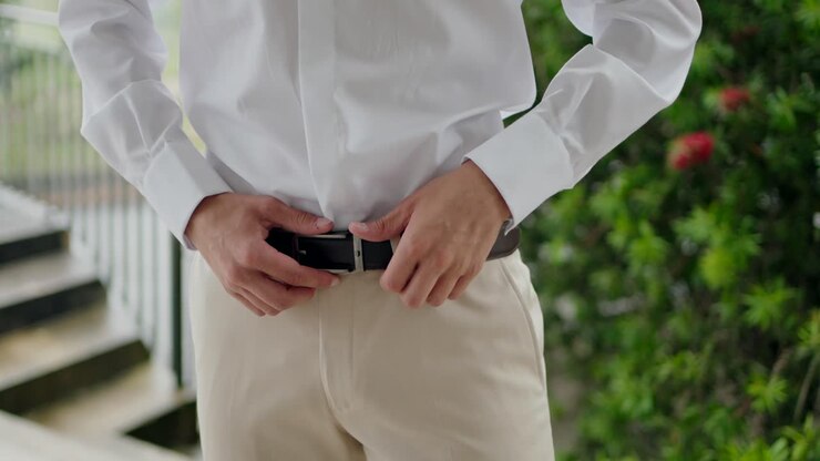 Uomo che si sistema la cintura prima di un matrimonio