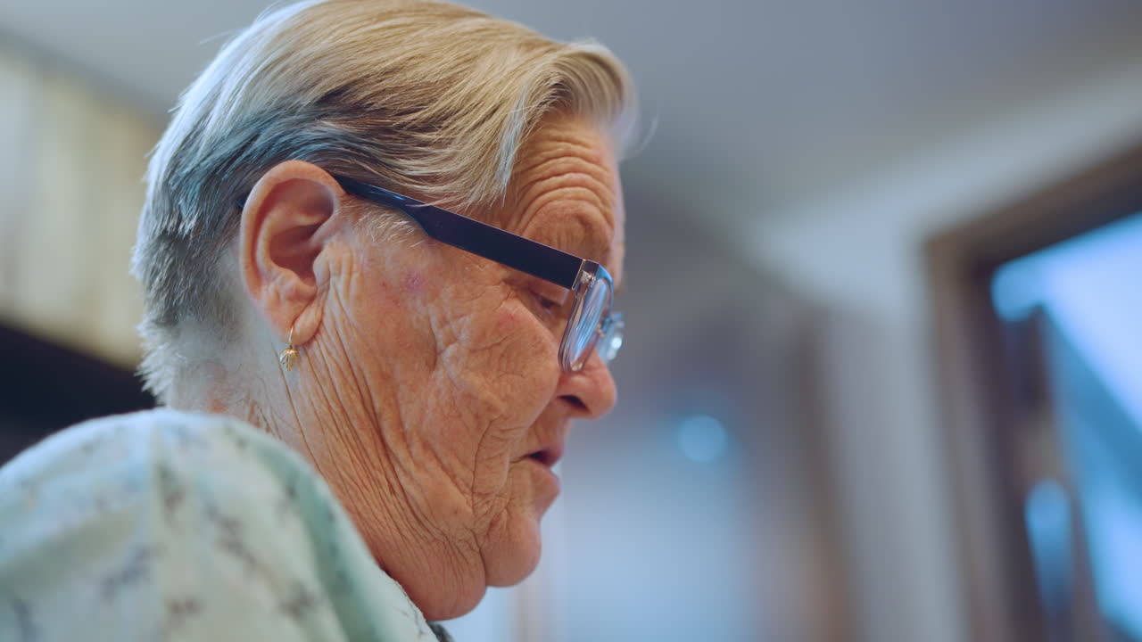 Donna anziana pensierosa. Nonna che guarda attraverso la finestra. Ritratto rispettoso di nonna riflessiva vicino alla finestra. Immagine intima che cattura una saggia donna anziana che si gode la tranquilla luce del mattino.