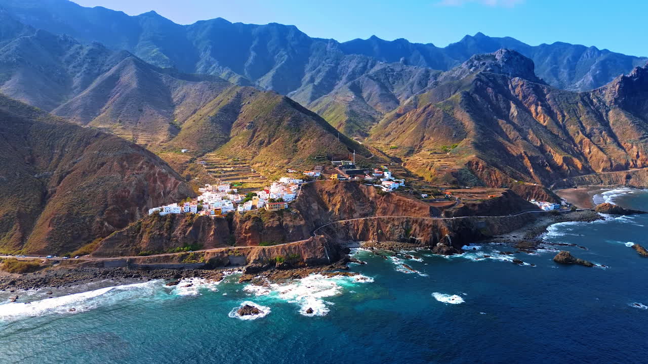 Approaching the rocky shore with villas located on top. Scenic view on the amazing mountainous landscape of Tenerife, the Canary Islands, Spain