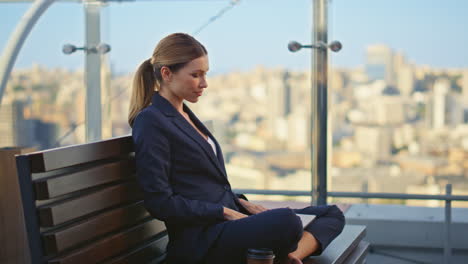 mujer remota navegando por el portátil en la terraza de la ciudad. gerente feliz terminando el proyecto