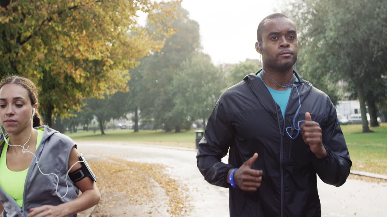 Athletic couple running in park wearing wearable technology connected devices