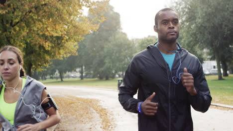 athletic couple running in park wearing wearable technology connected devices