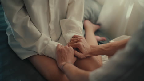 pareja cogida de la mano en la cama