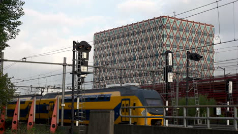 trains on the railway with city hall of gouda in netherlands in background