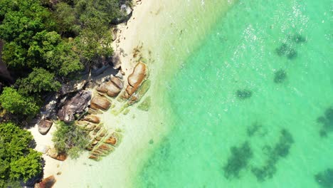 Crystal-emerald-water-of-turquoise-lagoon-caving-beautiful-limestone-cliffs-on-shore-of-tropical-island-with-lush-vegetation,-Ko-Tao,-Thailand