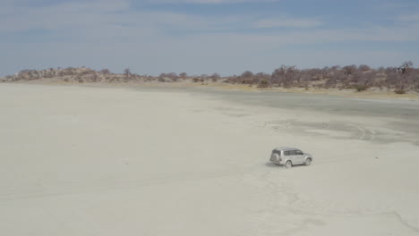 viajar en camión suv en el árido desierto en la isla de kubu, botswana con baobabs y salina en el fondo