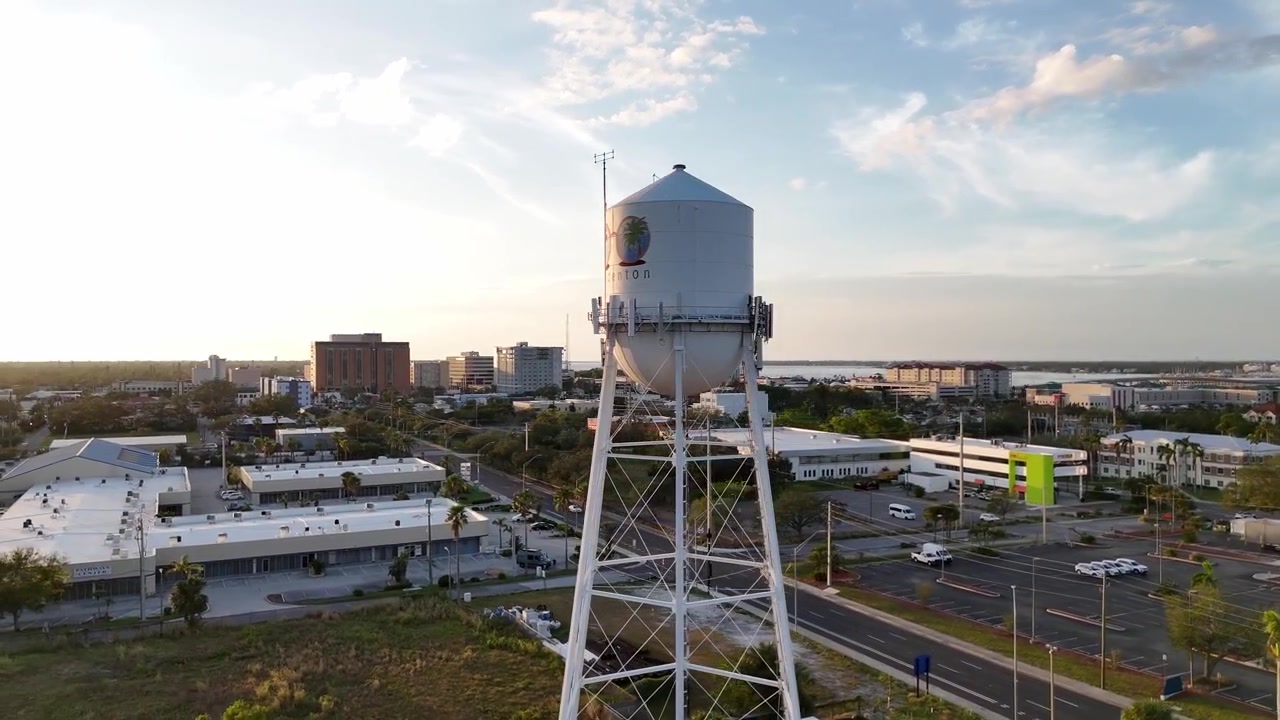 Orbitale Luftaufnahme des Wasserturms in Bradenton, Florida, während der goldenen Stunde, mit der umliegenden Stadt und dem Manatee River im Hintergrund.