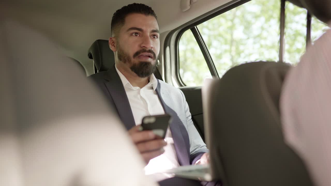 hombre usando portátil y teléfono inteligente en el coche