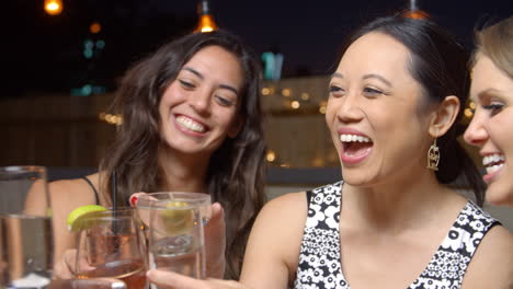 female friends enjoying night out at rooftop bar, slow motion