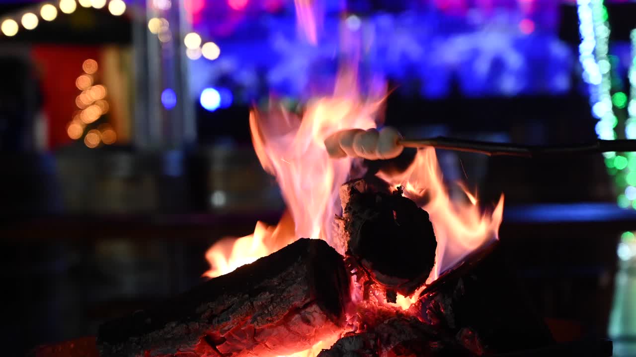 Close up of marshmallows warming up on a burning fireplace with Christmas decor on the background