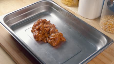 Medium-Shot-of-Adding-Tomato-Sauce-to-a-Baking-Tray-for-Making-Lasagne