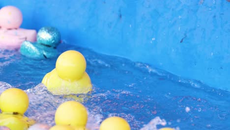 assorted rubber ducks drift in a blue water stream