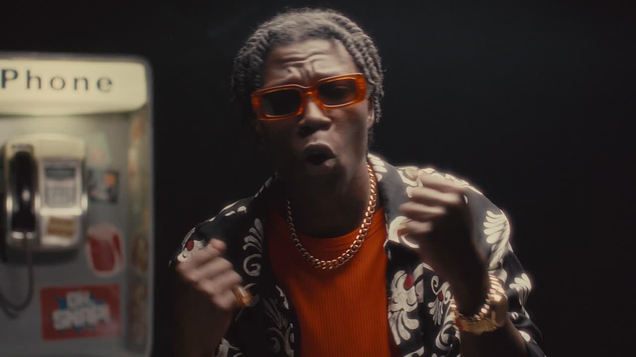 Black Man Rapping to Camera against Public Payphone in City Street