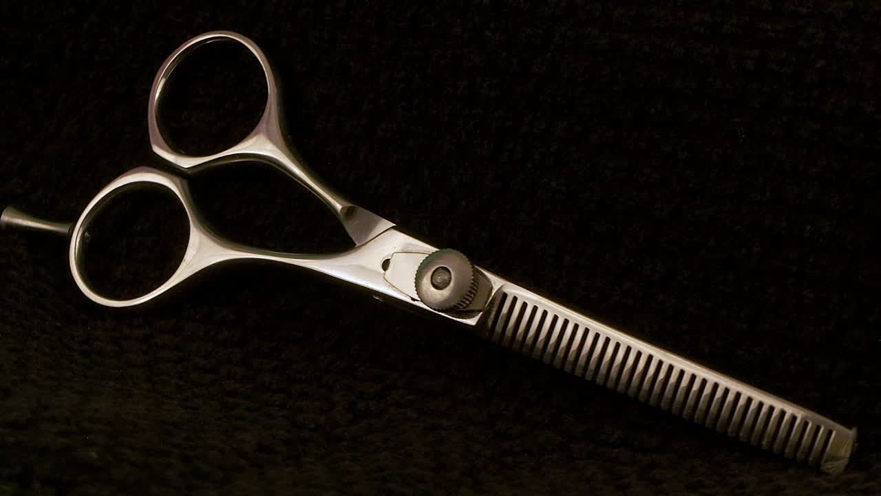 Macro closeup view of hairstylist thinning shears rotating on black