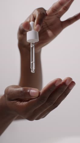 close up of woman squeezing dropper from bottle of beauty product on white background 5