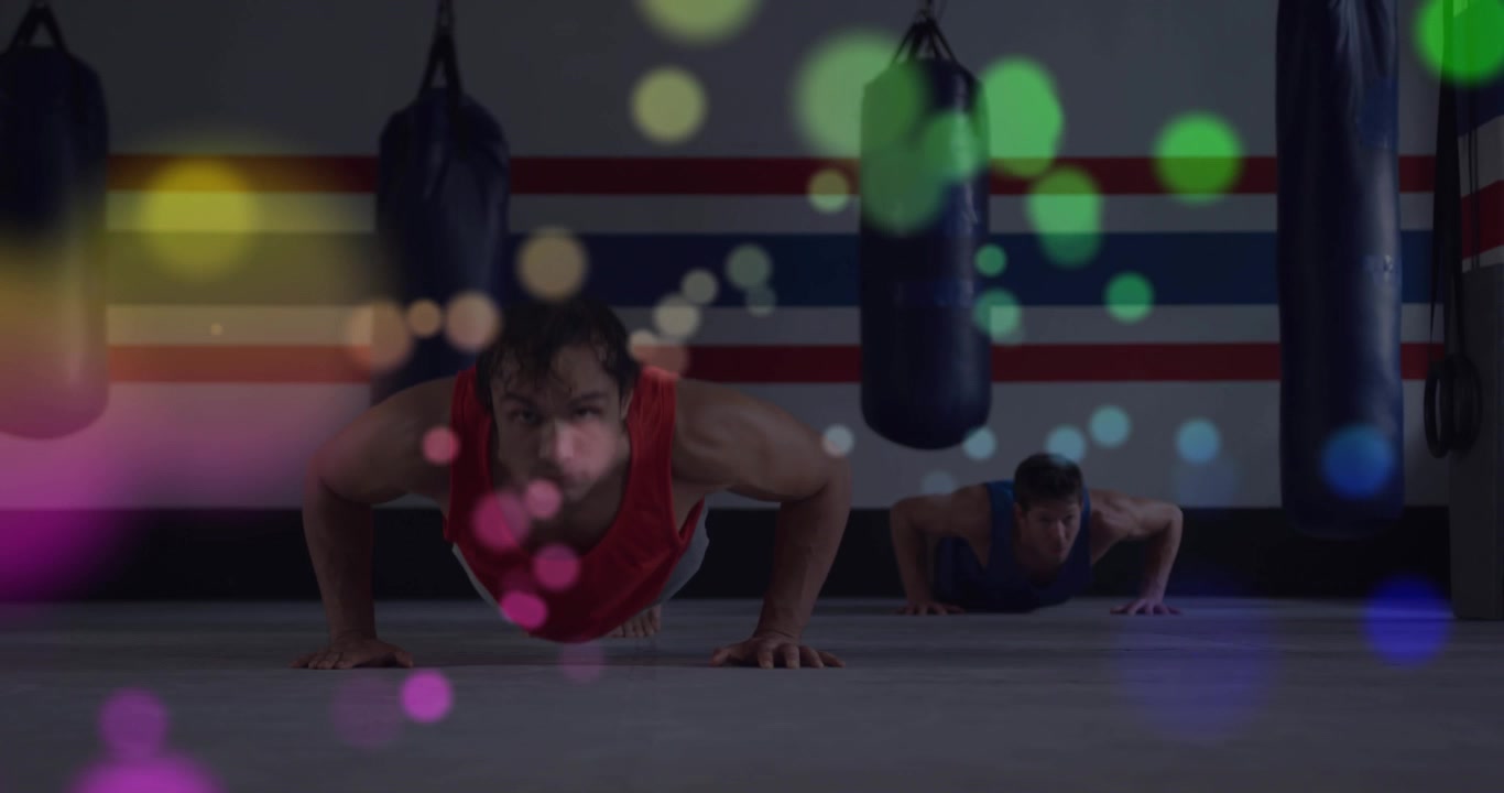 Front man tank initiating push-ups in boxing training near bags, rear man mirroring bokeh drifting