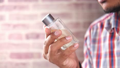 hombre sosteniendo y oliendo una botella de perfume