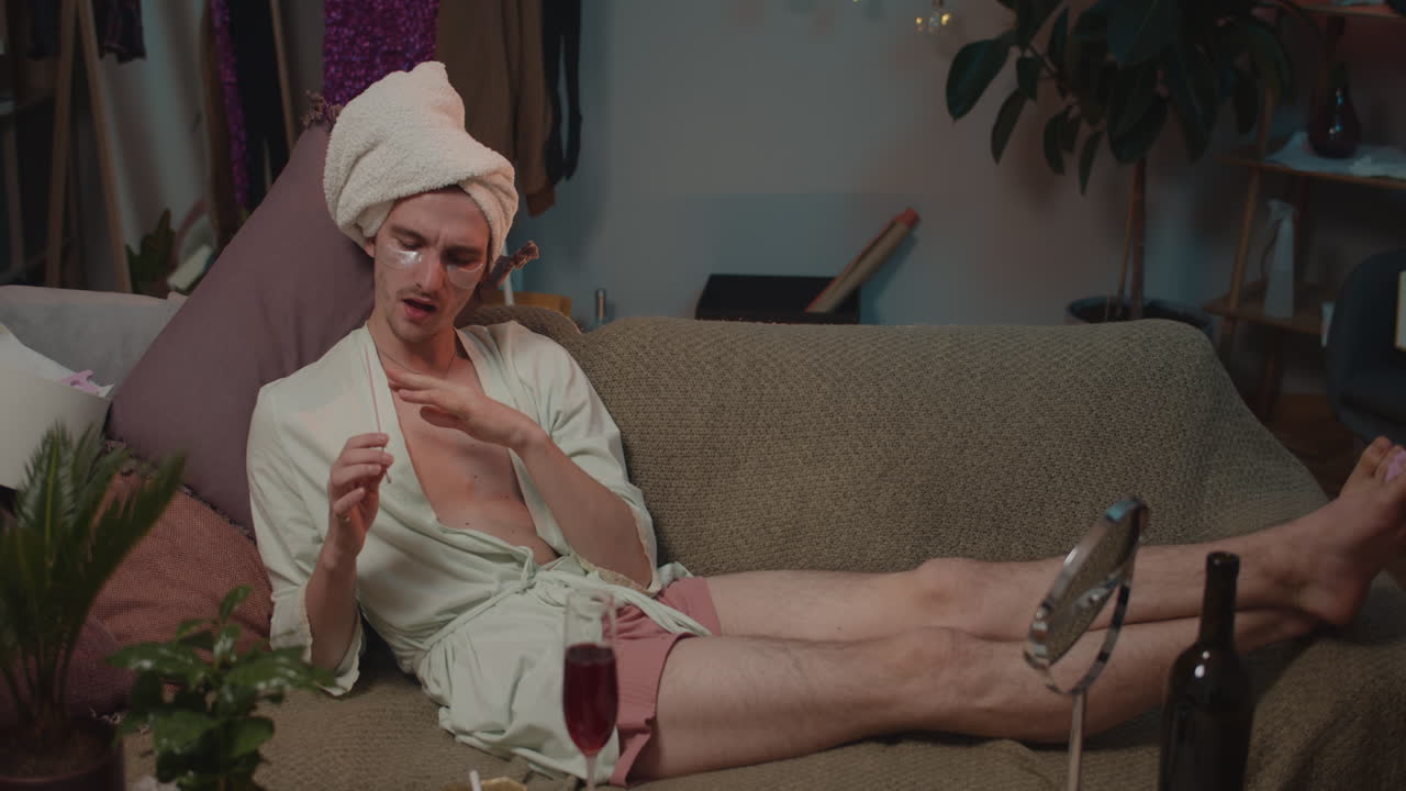 Man in robe and towel grooming on couch