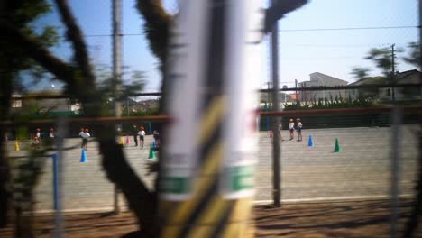 japanese kids making exercises at schoolyards at sunny day, view from car
