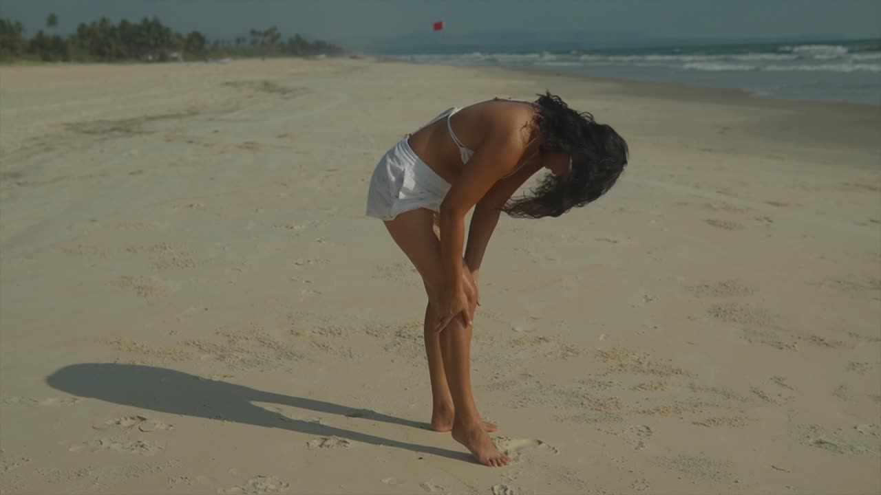 clip fijo de una mujer aplicando loción de bronceado a sus piernas en una playa soleada