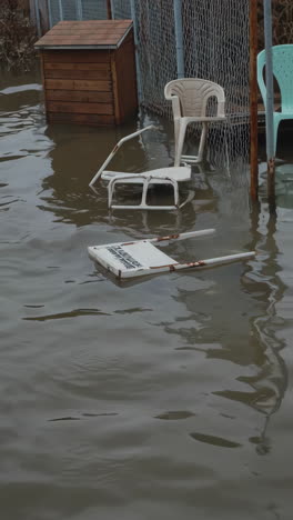 flooded backyard with submerged dog house and chairs