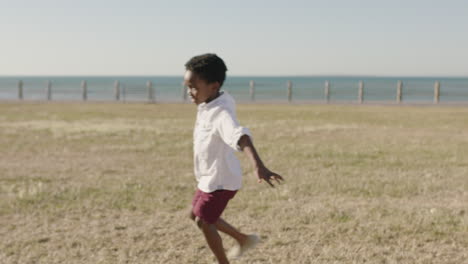 close up portrait of happy african american boy running playing arms raised enjoying summer fun at seaside park childhood imagination