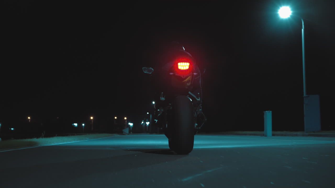 한 남자 가 밤 에 도시 를 가로질러 스포츠 오토바이 를 타고 있다