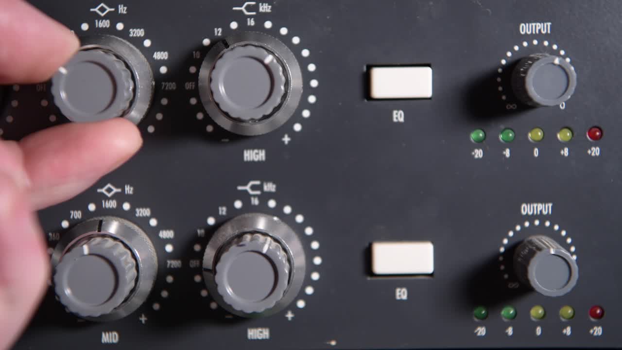 ajustando los diales de un preamplificador de micrófono antiguo durante una sesión de grabación en el estudio