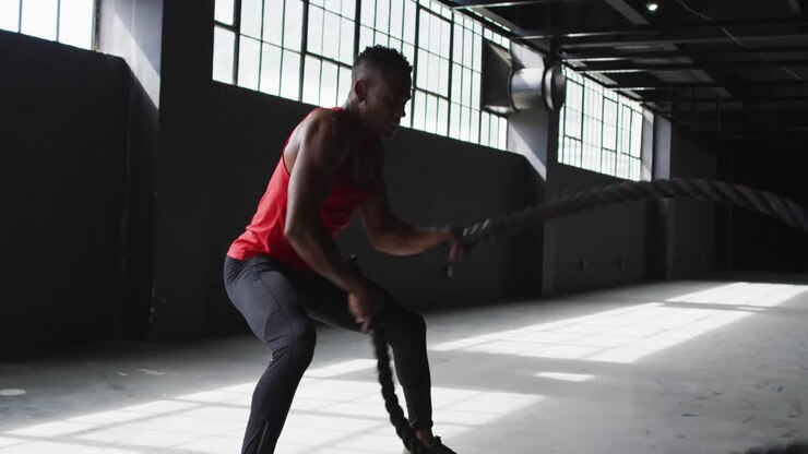 African american man exercising battling ropes in an empty urban building