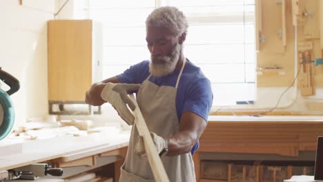 african american male carpenter looking and choosing wooden plank in a carpentry shop