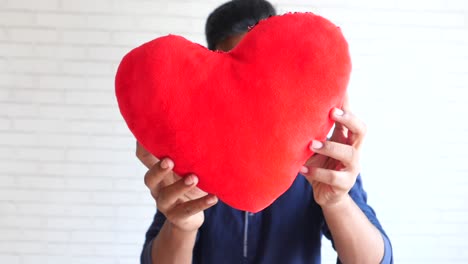 hombre sosteniendo una almohada roja en forma de corazón