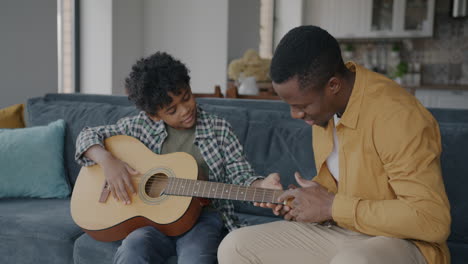 father and son learning guitar together at home