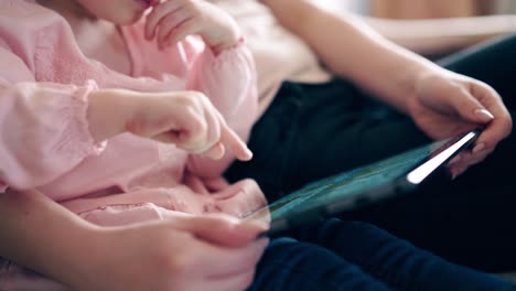 cu 4k young cute mother and little girl are sitting on the couch and teaching using a tablet computer