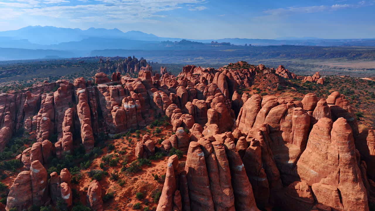 Paesaggio cinematografico di meravigliose rocce colonnari con cime arrotondate. Piccoli arbusti verdi crescono intorno. Vista illuminata dal sole del Parco nazionale degli Arches nello Utah, USA, da drone