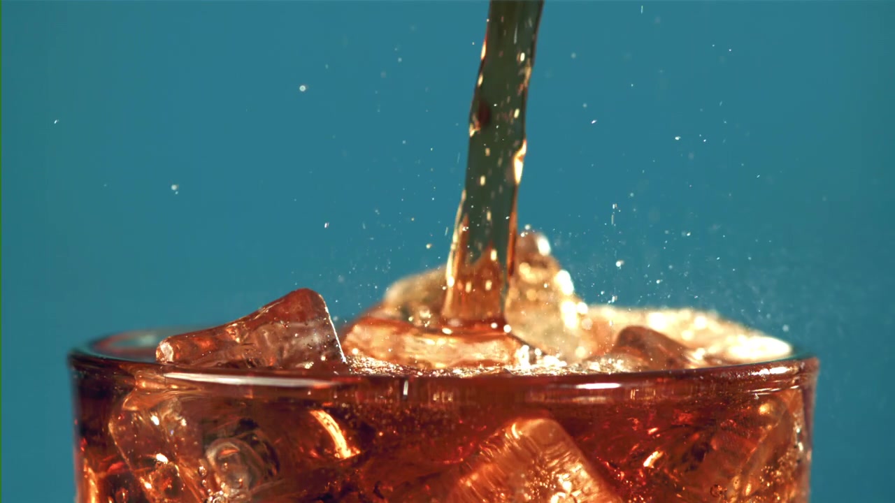 氷の入ったグラスに爽やかなコーラが注がれるスローモーション