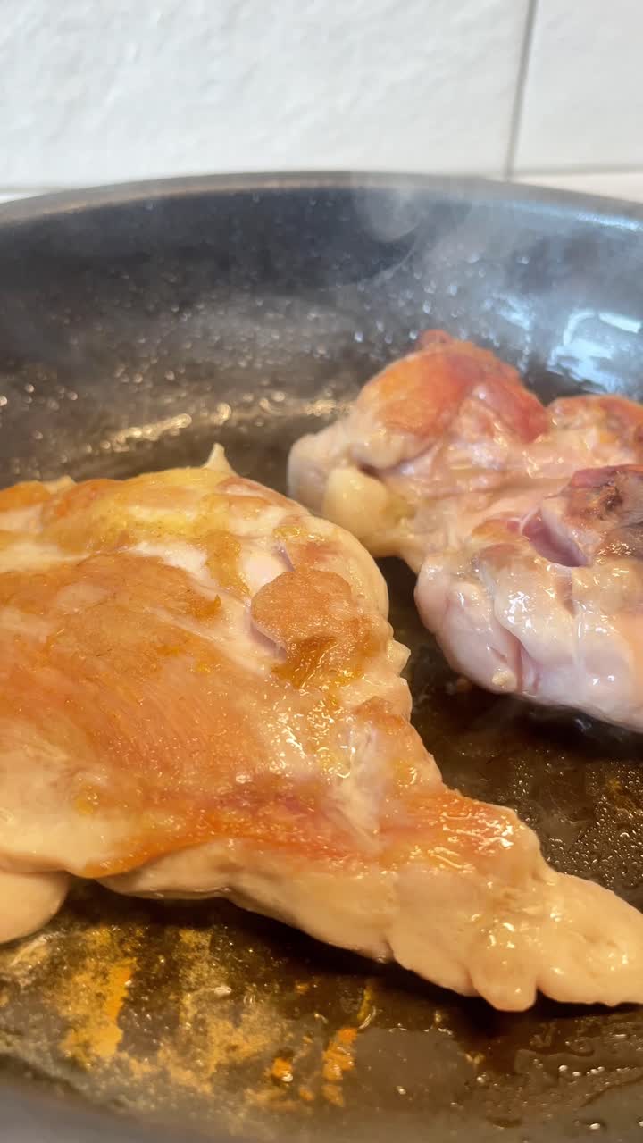 Due pezzi di carne cuociono in padella. La carne è rosolata e ha una consistenza croccante