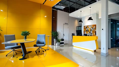 a yellow and white reception area in an office with a couch, table and chairs