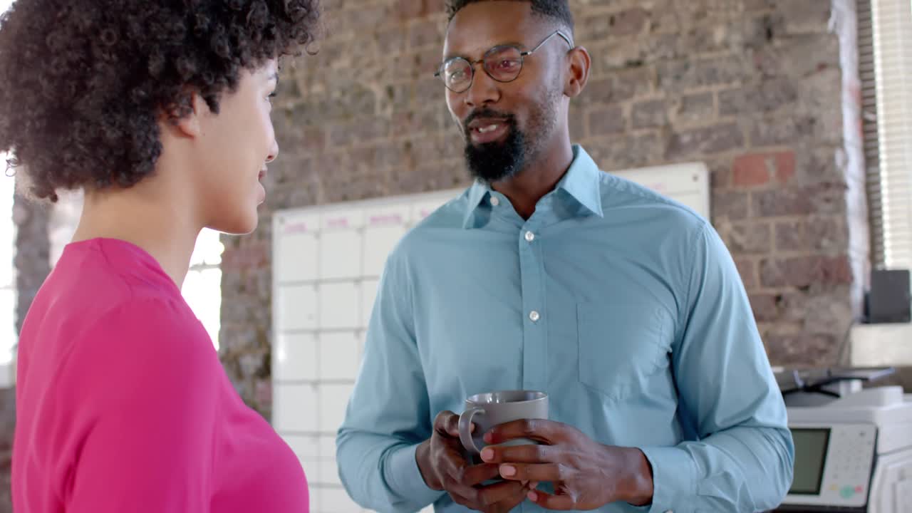 Happy diverse colleagues talking and drinking coffee in office in slow motion