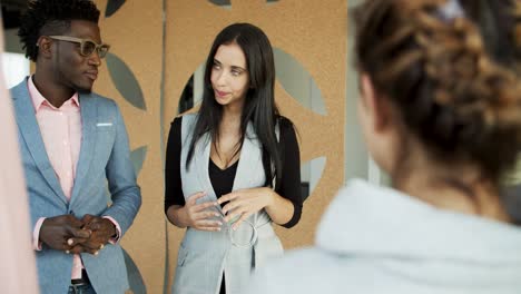 Cheerful-colleagues-standing-in-circle-and-talking