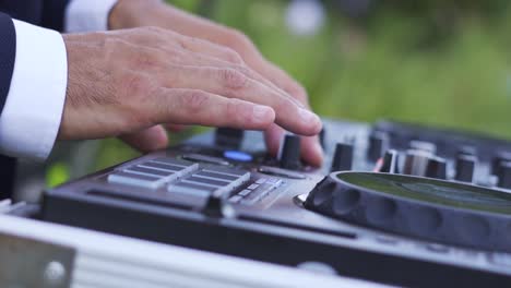 close up of dj's hands pressing buttons on a music table at wedding party