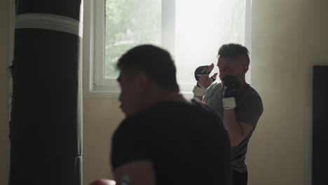 los atletas se ejercitan con bolsas de boxeo en el club deportivo. las siluetas de deportistas hábiles patean y golpean equipos pesados en el gimnasio de lucha en cámara lenta. equipo de artes marciales