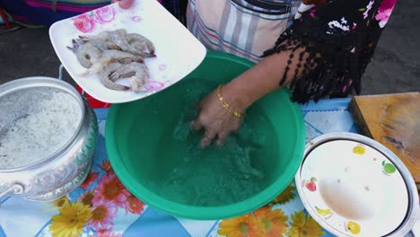 mujer tailandesa poniendo gambas en un plato después de limpiarlas en un tazón