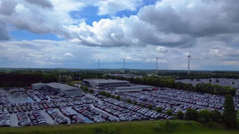large parking lot full of cars near a wind farm and countryside in germany. best aerial view flight rotation to right drone