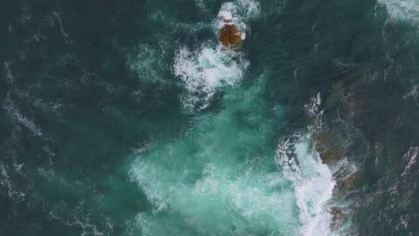 top down shot of waves crashing smoothly on rocks, mirador de monteferro, vigo, galicia, spain