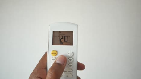 close up of a hand holding a remote control of an air conditioner