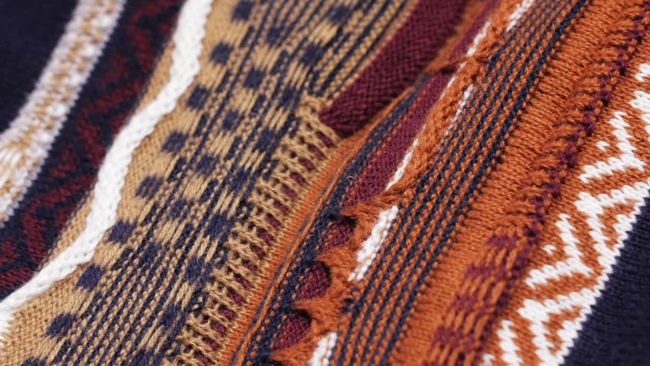 Macro pan across patterned knit sweater fabric with textured weave