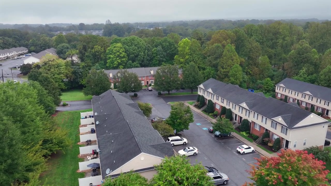 Ripresa aerea in avvicinamento di un'area residenziale con piccoli giardini in periferia. Giornata autunnale buia e nebbiosa in America. Ripresa dall'alto. Auto parcheggiate nell'area di sosta della comunità