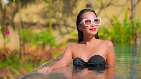 Retrato-De-Una-Mujer-Morena-Sonriente-Feliz-En-Traje-De-Baño-Negro-Relajándose-Dentro-De-La-Piscina-Y-Mirando-A-Un-Lado-En-El-Resort-De-Tailandia