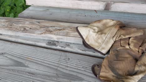 un par de viejos guantes de trabajo de cuero desgastados sobre una litera de tablas desgastadas de dos por cuatro