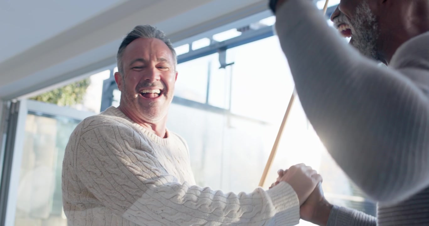 Man wearing sweater is lining, striking cue trying to sink ball on pool table, friends celebrating